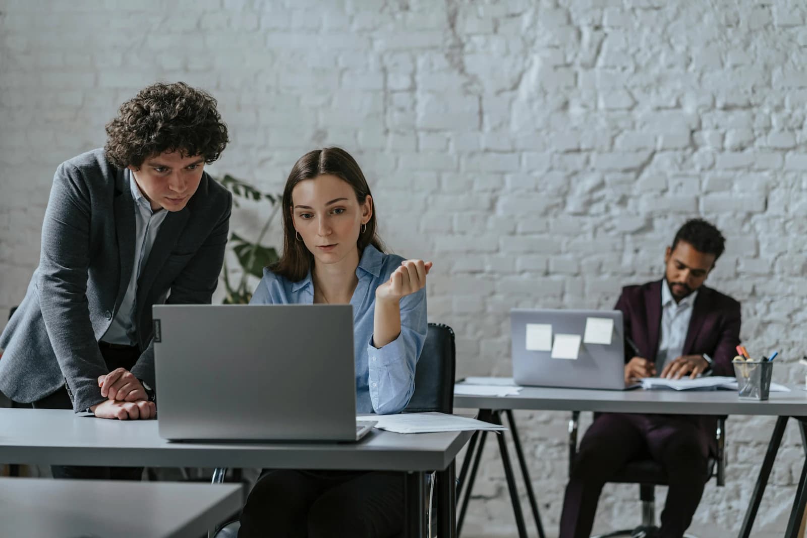 Compañeros de oficina revisando juntos un portátil, el día a día de un equipo que trabaja con las apps de Zoho