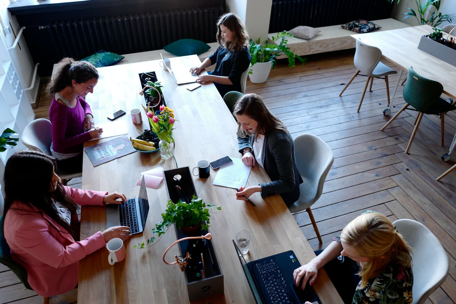 Equipo trabajando con portátiles en una mesa larga de madera, la conversación previa a decidir si dejar Odoo por ERPNext