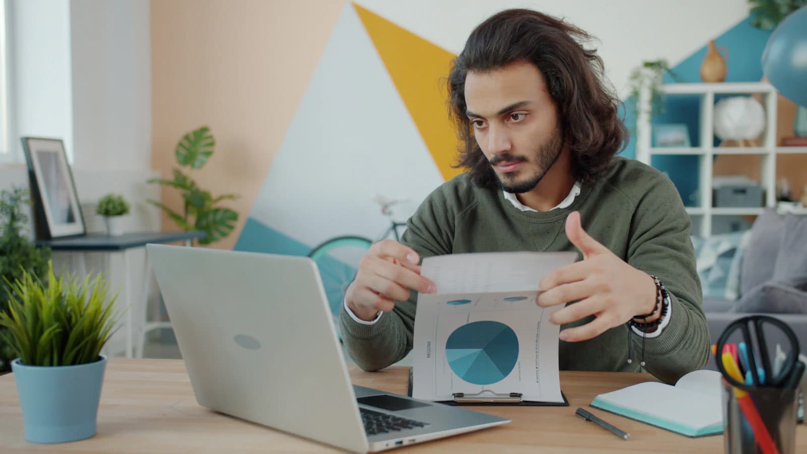 Hombre revisando un informe con gráfico de sectores junto a su portátil, haciendo números antes de migrar de Zoho a ERPNext