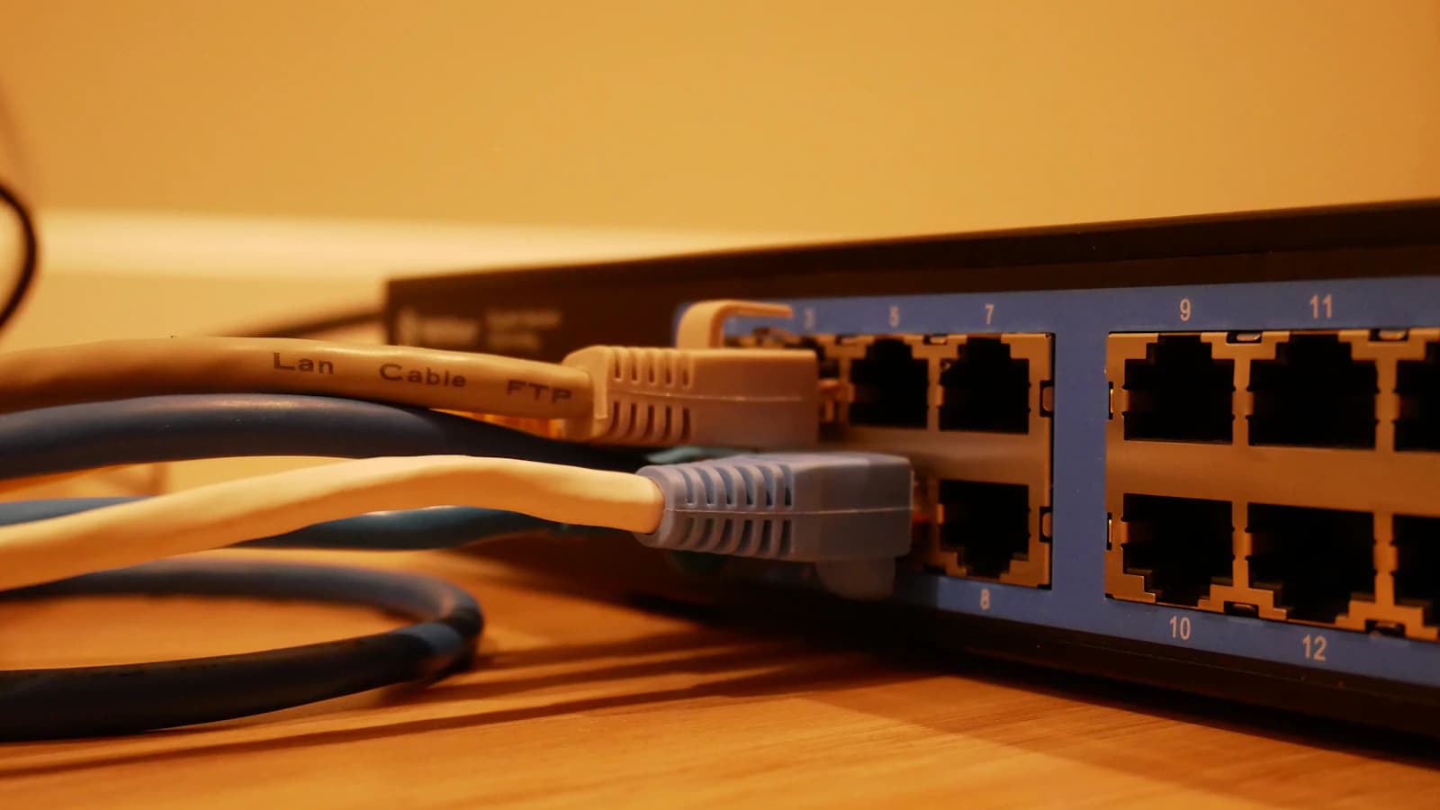 Switch de red con cables Ethernet conectados sobre una mesa de madera, la infraestructura por la que viaja el envío SOAP a la AEAT