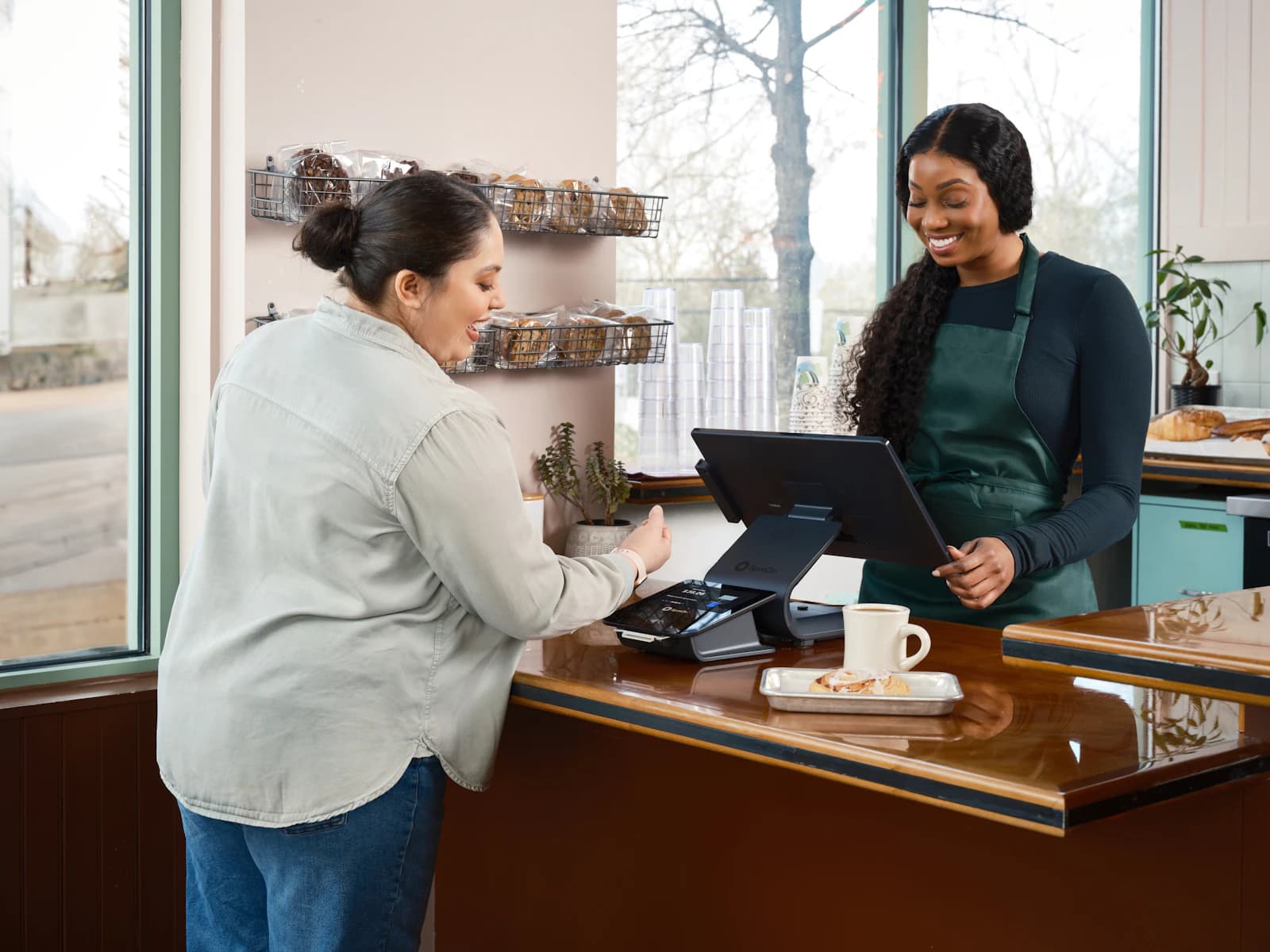 Clienta pagando en el mostrador de una cafetería con terminal de venta, el tipo de operación cuyo ticket registra TicketBAI