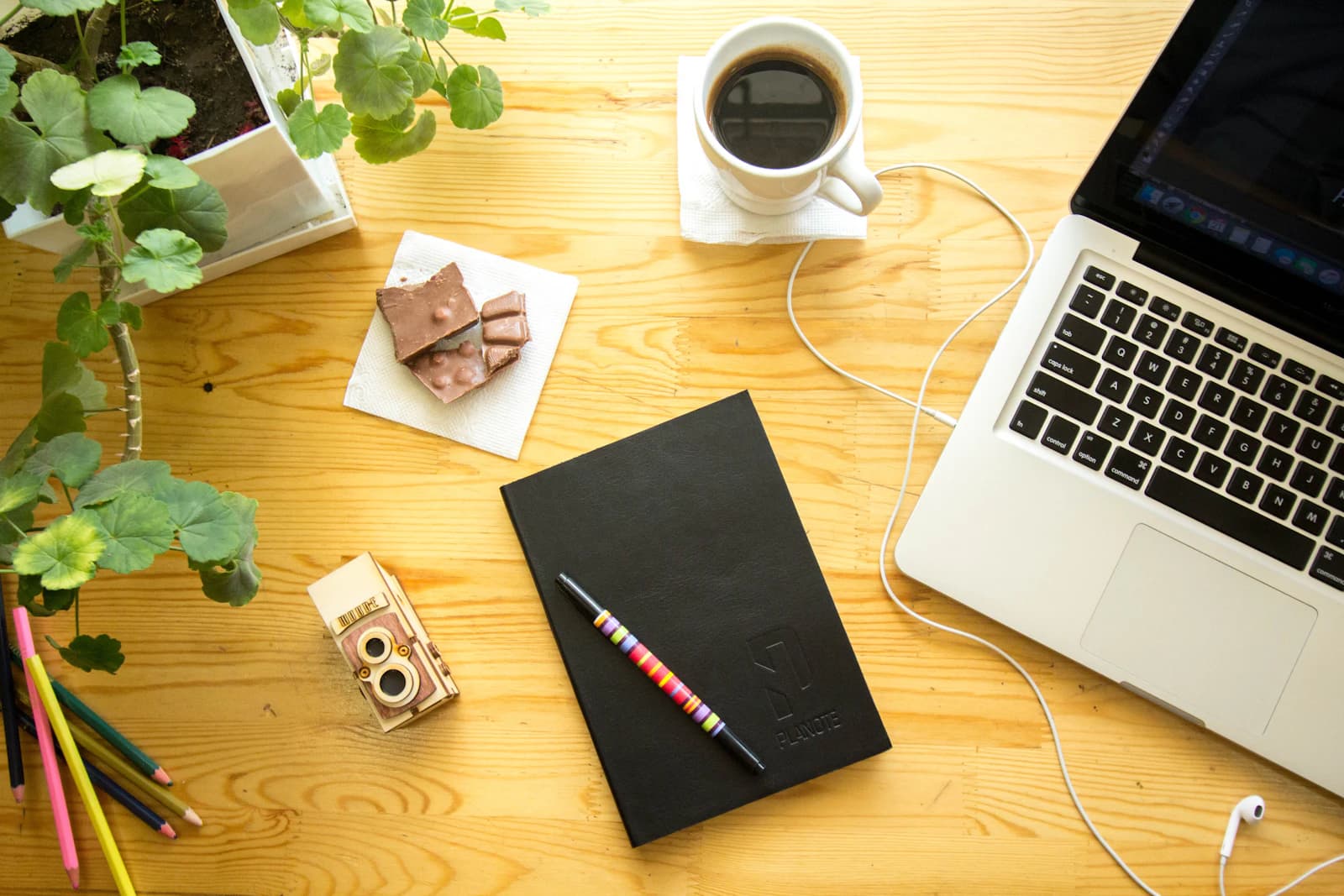 Escritorio de madera con portátil, cuaderno y café para repasar la cifra de partida de ERPNext frente a la cuota de Sage