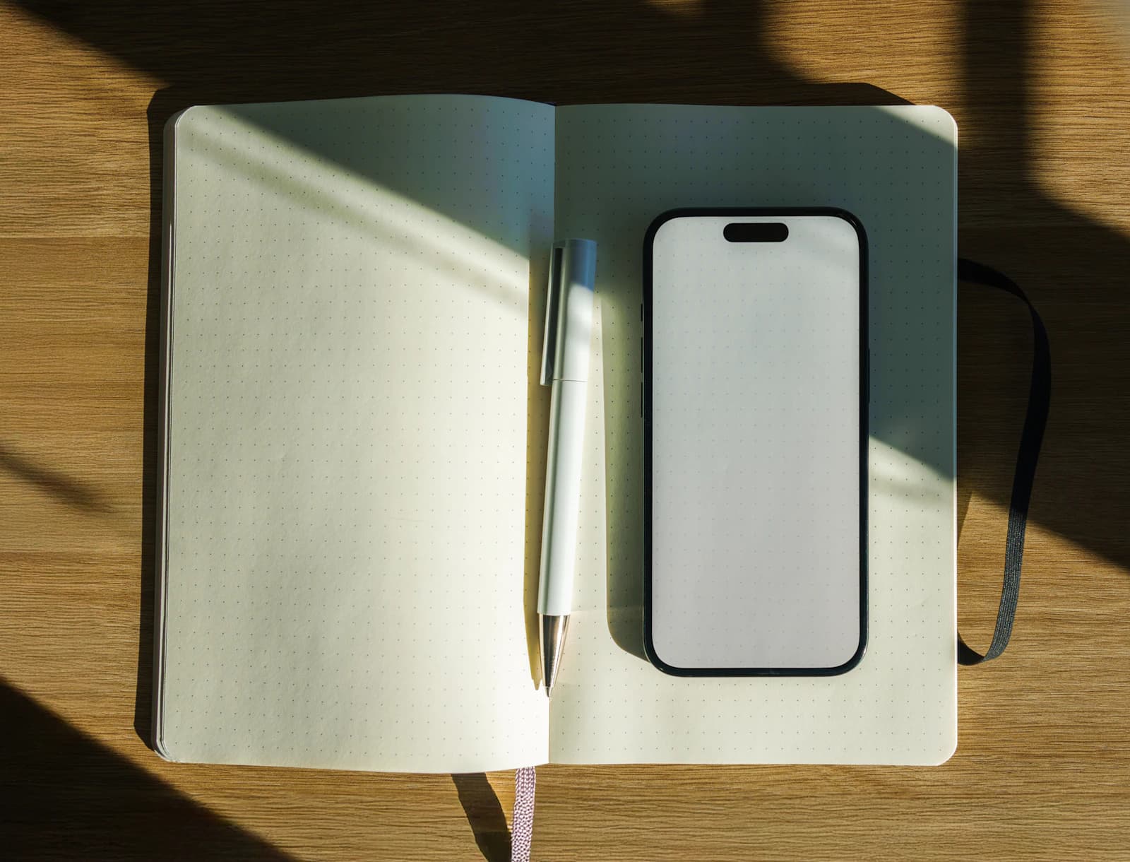 Cuaderno abierto con bolígrafo y móvil sobre una mesa de madera, para preparar lo que quieres contarnos de tu proyecto ERPNext