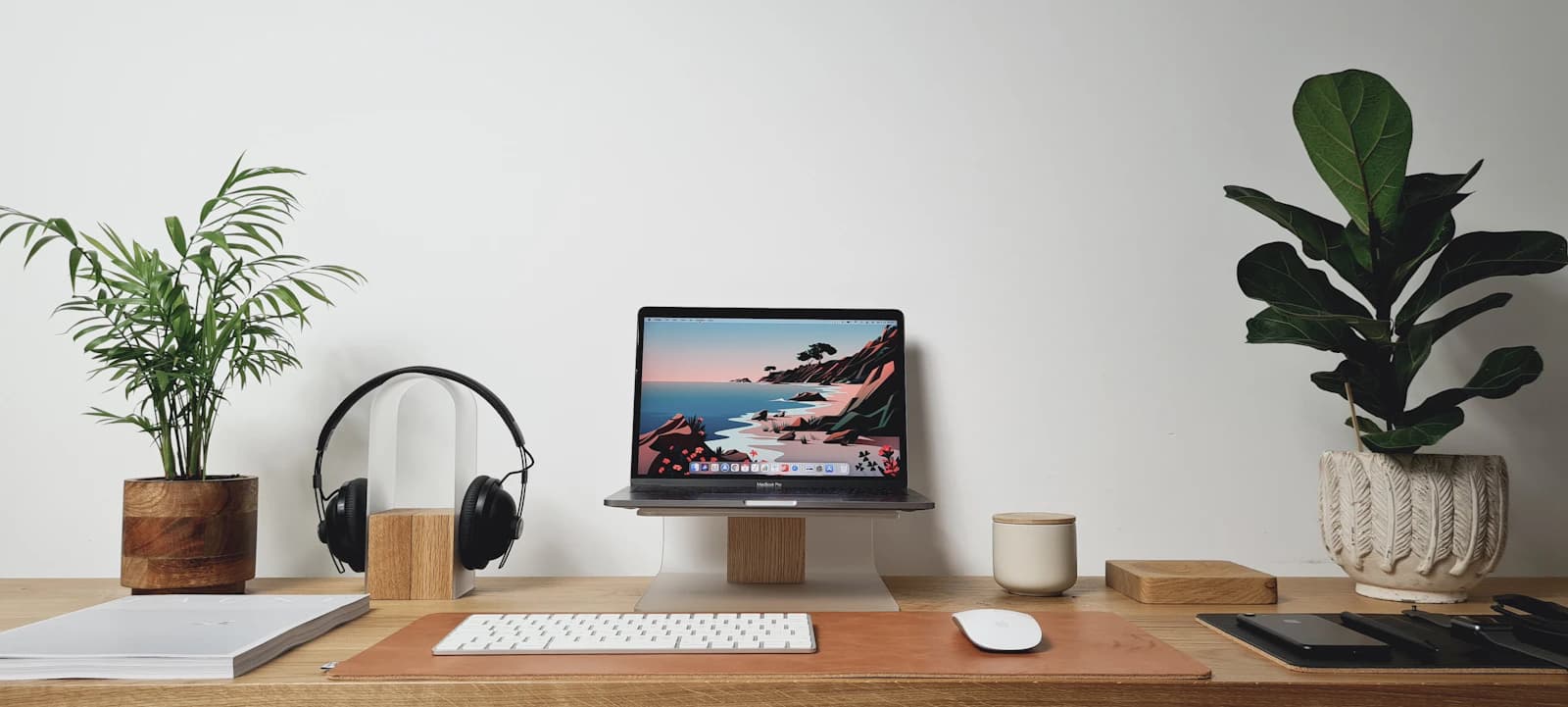 Mesa de teletrabajo con portátil, auriculares y plantas: reuniones por videoconferencia en lugar de oficina y sala de reuniones
