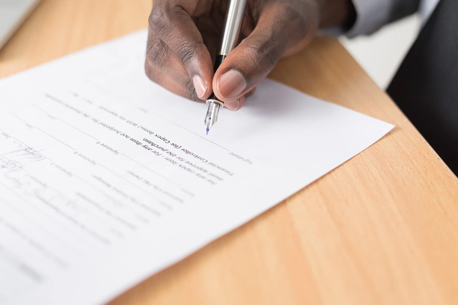 Mano firmando un documento sobre una mesa de madera, como el presupuesto cerrado por escrito de una implantación de ERPNext
