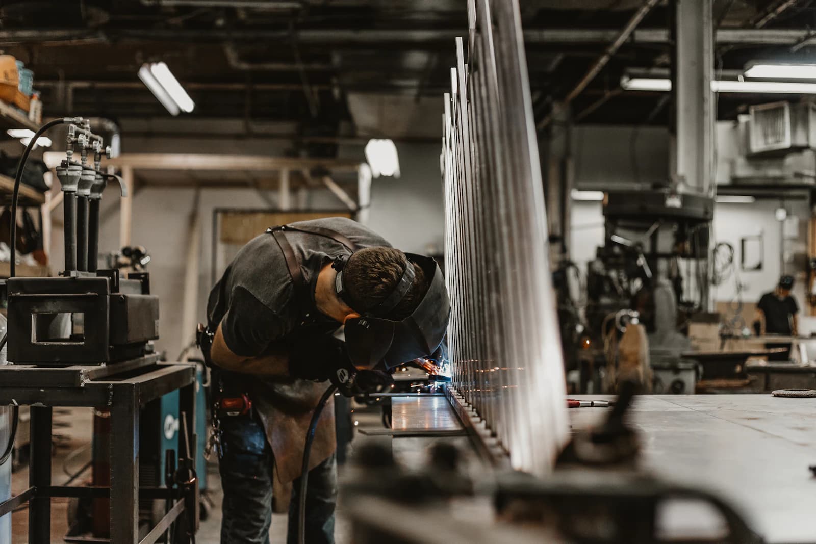 Soldador trabajando estructuras metálicas en un taller de fabricación, el tipo de producción que planifica un software MRP