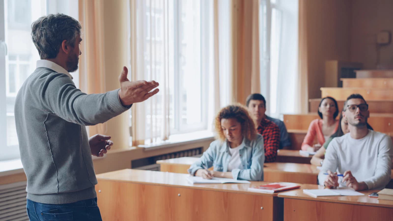 Profesor explicando a un grupo de alumnos adultos en un aula luminosa, el tipo de centro que organiza un ERP para academias