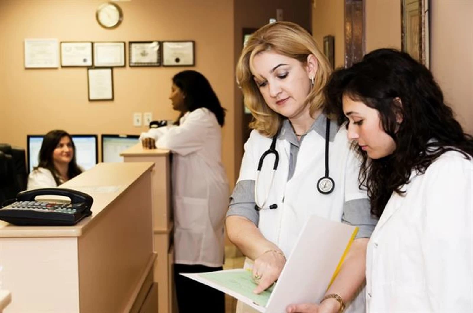 Doctoras revisando un informe junto al mostrador de recepción de una clínica, el día a día que ordena un ERP para clínicas