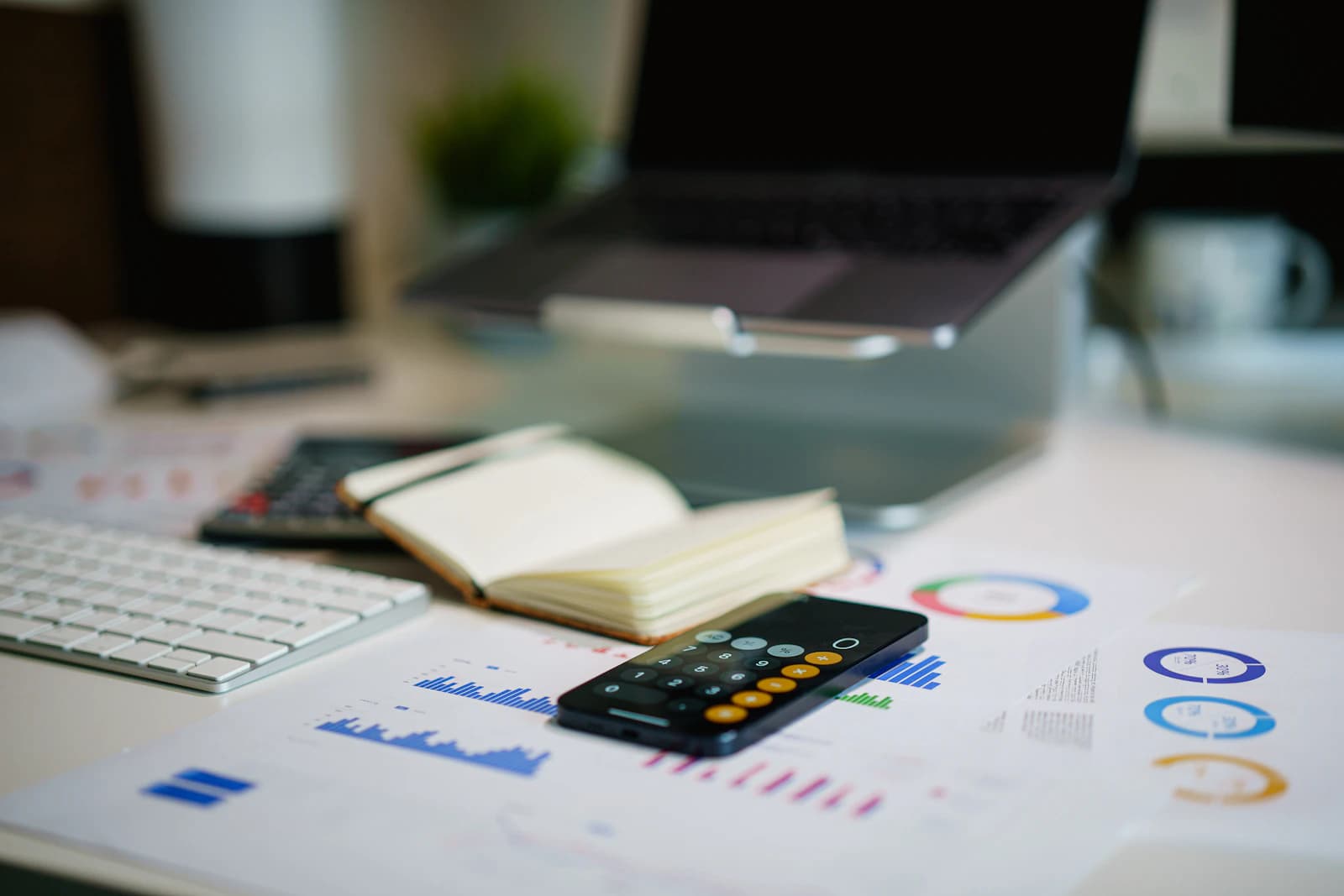 Mesa de trabajo con informes de gráficos, calculadora y cuaderno abierto, la revisión del presupuesto de implantación