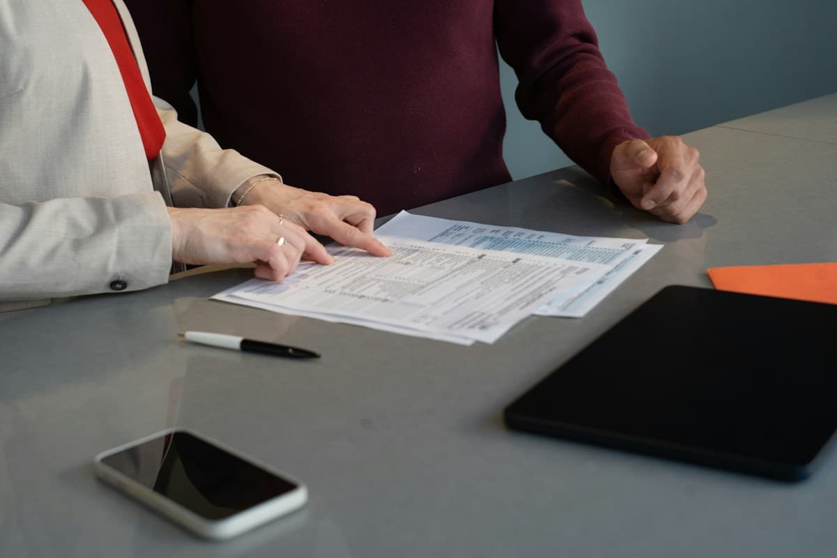 Dos personas repasan sobre la mesa un documento impreso con un bolígrafo al lado, como en la revisión de una consultoría ERPNext