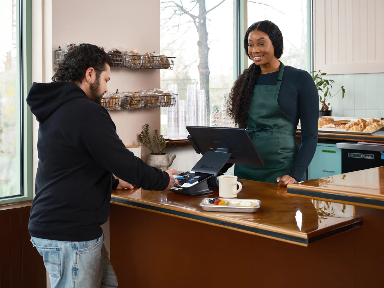 Cliente pagando con tarjeta en el mostrador de una cafetería, el punto donde VeriFactu cambia el ticket del comercio